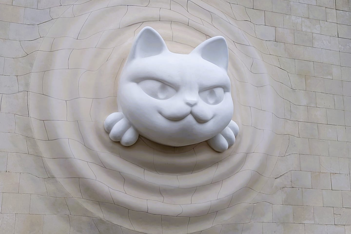 A large white cat sculpture pushing head first out of the tiled wall of pavilion 9 at VDNH