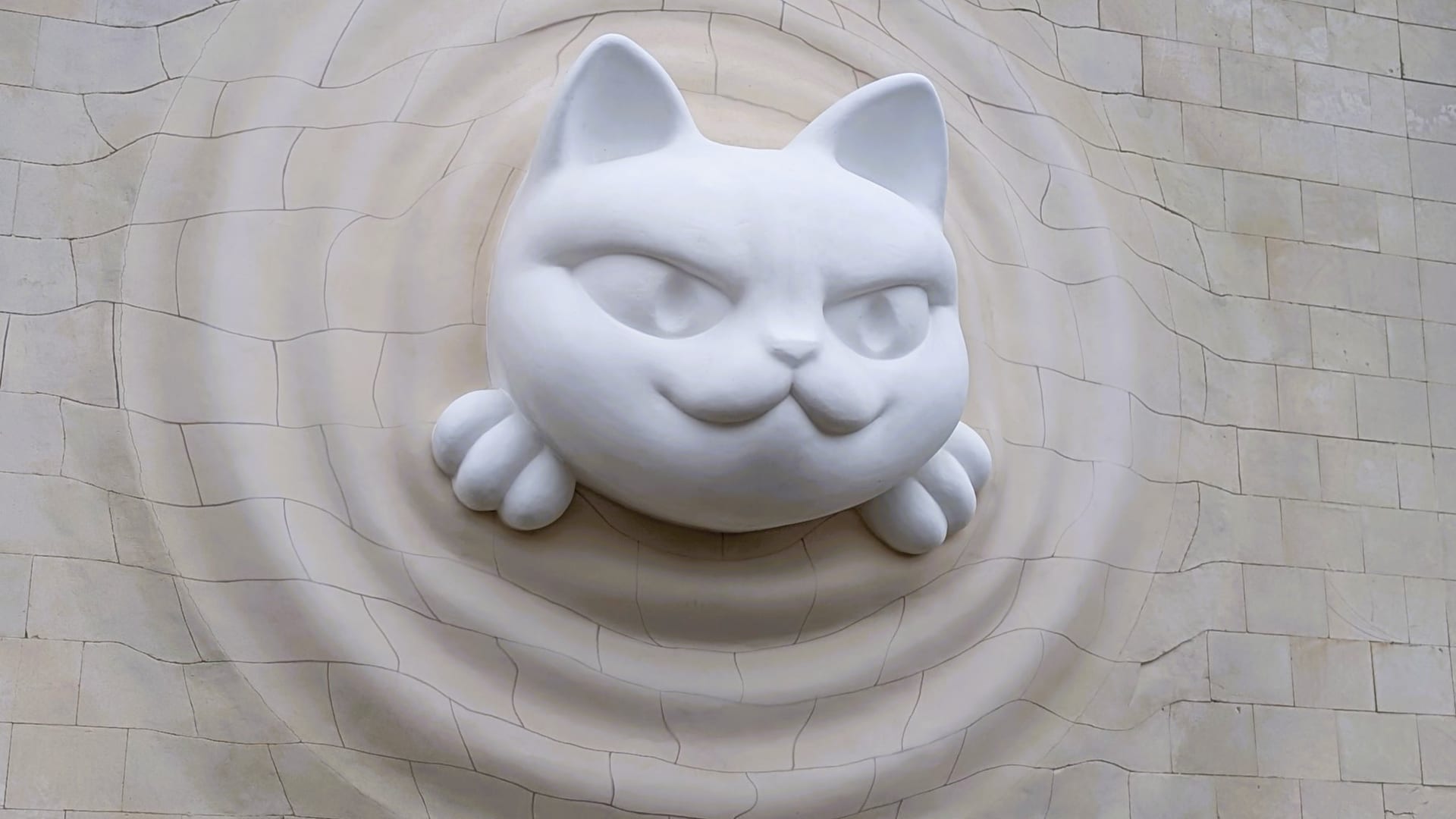 A large white cat sculpture pushing head first out of the tiled wall of pavilion 9 at VDNH